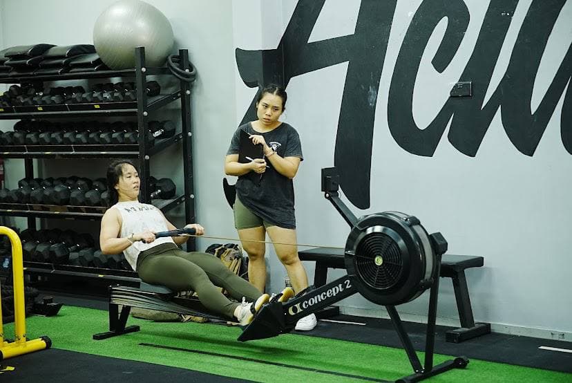 Eugenia Chan coaching client on rowing machine at Actualize CrossFit Singapore