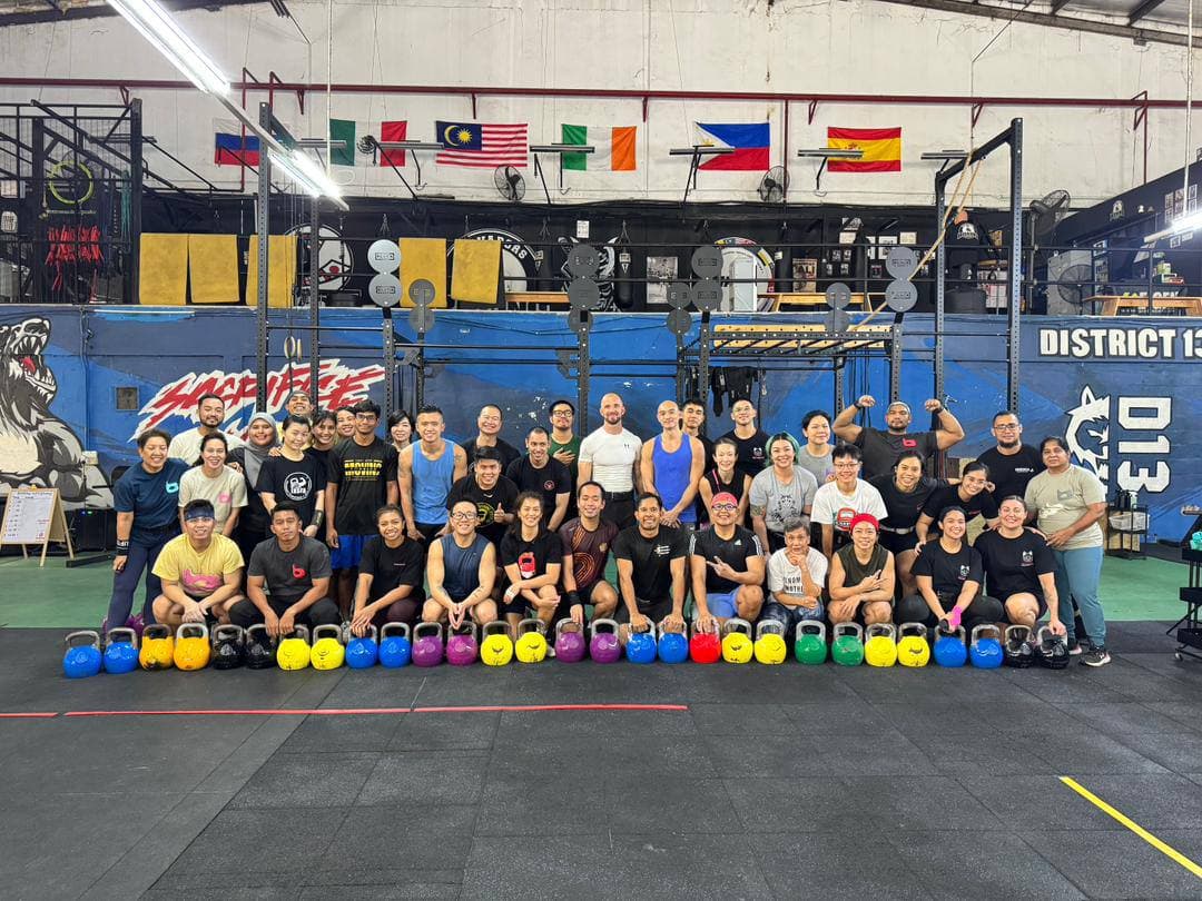 Large group at District 13 kettlebell workshop with colorful kettlebells in Singapore
