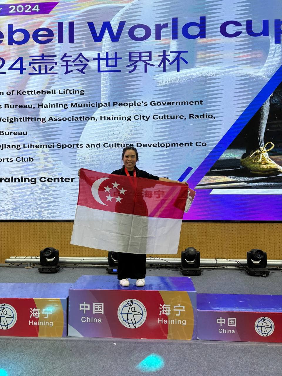 Eugenia Chan with Singapore flag at IUKL Kettlebell World Cup 2024 China podium