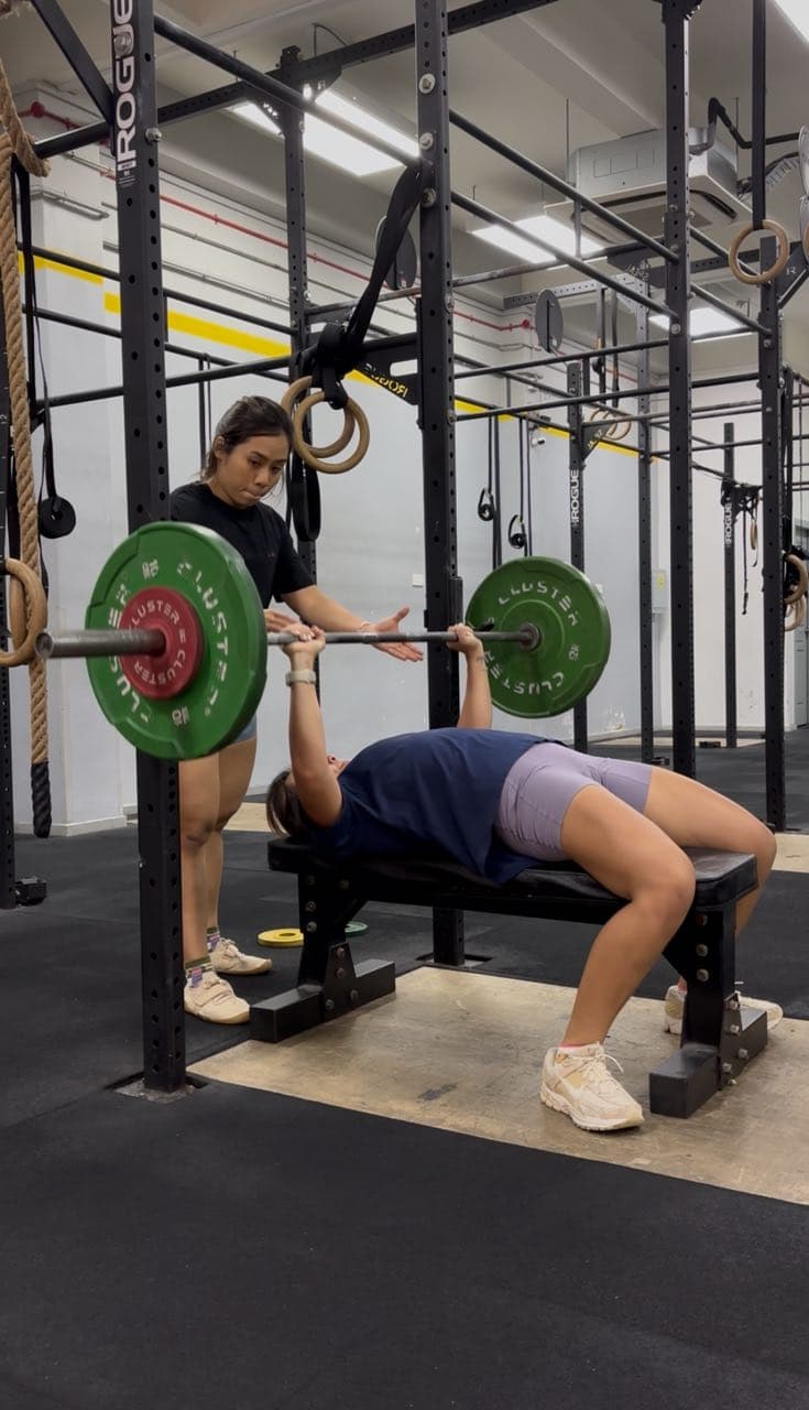 Eugenia Chan personal training session spotting client on bench press in Singapore
